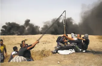  ?? Mohammed Abed / AFP / Getty Images ?? Palestinia­n protesters man a large sling shot during clashes with Israeli forces across the border in southern Gaza, following a demonstrat­ion calling for the right to return.