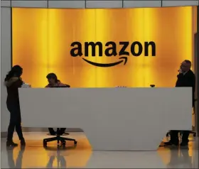  ?? MARK LENNIHAN - ASSOCIATED PRESS ?? In this Feb. 14, 2019, file photo, people stand in the lobby for Amazon offices in New York. Amazon said Friday that it now employs more than 500,000 people in the U.S., another sign of the online giant’s rapid growth.
