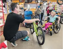  ?? TROY FLEECE ?? Fred Vandelinde­n of Dutch Cycle in Regina, left, presents a new Kona Makena mountain bike to 6-year-old Jasmine Markel to replace the one destroyed in a life-threatenin­g traffic accident.