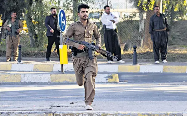  ??  ?? A member of the Kurdish Peshmerga runs in the street in Kirkuk after an attack by Isil militants. Reinforcem­ents have been sent to the city which was targeted in the wake of an army offensive on Mosul, another northern city