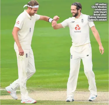  ??  ?? All smiles: Chris Woakes celebrates with Stuart Broad after taking Shannon Gabriel’s wicket