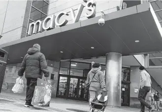  ?? Charles Krupa / Associated Press ?? Shoppers walk to the Macy’s in Boston’s Downtown Crossing district. Americans slowed their spending in November from October, but they again showed resilience against higher prices and store shortages.