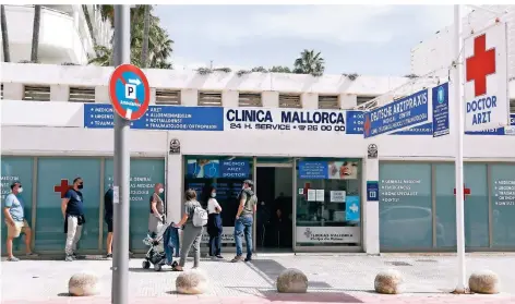  ?? FOTO: CLARA MARGAIS/DPA ?? Menschen warten vor einem Covid-19-Testzentru­m am Strand von El Arenal auf Mallorca.