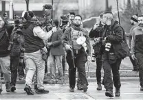  ?? Paul Sancya / Associated Press ?? A protester carrying a rifle leaves the Kenosha County Courthouse after speaking with officers on Wednesday.