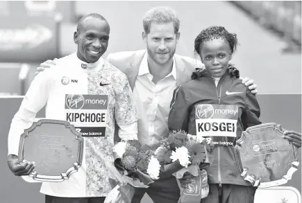  ??  ?? Britain’s Prince Harry, Duke of Sussex, is flanked by men’s race winner Kenya’s Eliud Kipchoge (L) and women’s race winner, Kenya’s Brigid Kosgei (R) at the medal ceremony at the 2019 London Marathon. - AFP photo