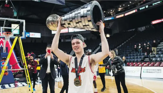  ?? DARREN CALABRESE/THE CANADIAN PRESS ?? Andrew Milner hoists the W.P. McGee Trophy after the Dinos defeated Ryerson 79-77 Sunday to win their first U Sports men’s basketball title.