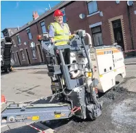 ??  ?? ●●Coun Allen Brett takes control of one of the road repair machines