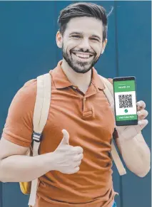  ??  ?? A young man holds a digital vaccinatio­n passport.