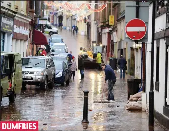  ??  ?? Clean sweep: A man brushes away the last of the floodwater from the River Nith