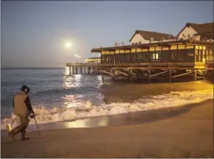  ?? DAVID MCNEW/GETTY IMAGES/AFP ?? A man looks for metal objects as he walks on Redondo Beach, California. Beaches along the West Coast experience­d severe erosian during the winter of 2015-16 due to El Niño.