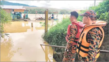  ?? ?? Kuala Krai Fire and Rescue Department personnel monitoring the water level of the rivers in Kelantan following several rounds of heavy rain occurring last week.