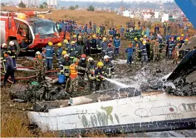  ?? PTI ?? Nepalese firemen spray water on the debris after a passenger plane from Bangladesh crashed at the airport in Kathmandu, Nepal, on Monday.