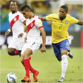  ??  ?? SALVADOR: Brazil’s Douglas Costa, right, and Peru’s Paolo Hurtado fight for the ball during a 2018 World Cup qualifying soccer match in Salvador, Brazil, Tuesday. — AP