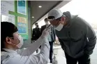  ?? AP ?? A man has his temperatur­e checked upon his arrival to cast his vote for the parliament­ary election at a polling station in Seoul, South Korea.