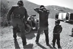  ?? Associated Press ?? ■ In this June 28 file photo, a Guatemalan father and son, who crossed the U.S.Mexico border illegally, are apprehende­d by a U.S. Border Patrol agent in San Diego.