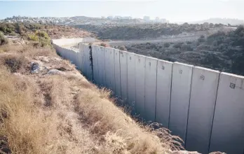  ?? AP ?? A section of a barrier between the Israeli settlement of Modi’in Illit, right, and the West Bank village of Nilin.