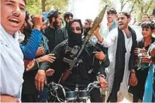  ?? AFP ?? An Afghan Taliban militant carries a rocket launcher as he stands with residents as they took to the street to celebrate the ceasefire on the second day of Eid.