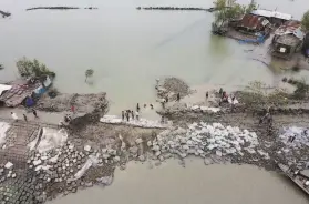  ?? Munir Uz Zaman / AFP / Getty Images ?? Volunteers and residents work to fix a dam damaged by Cyclone Amphan in Burigoalin­i, Bangladesh. More than 80 people have been killed.