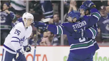  ?? — THE CANADIAN PRESS ?? Canucks teammates Daniel Sedin and Troy Stecher celebrate a first-period goal in Vancouver’s win over the Toronto Maple Leafs on Saturday.