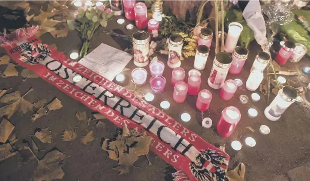  ??  ?? 0 Flowers, candles and an Austria scarf are left at a memorial site at the scene of the attack in Vienna when a gunman b opened fire, killing four people