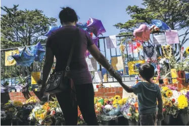  ?? Amy Osborne / Special to The Chronicle ?? Marie Chen and son Damien Wu, 4, read messages left for Mike Lefiti at a memorial in San Francisco’s Diamond Heights. Lefiti was one of three people killed by a gunman at a UPS distributi­on center last week.