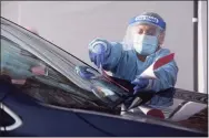  ?? H John Voorhees III / Hearst Connecticu­t Media ?? Lourdes Coronel places paperwork under the windshield wipers of a client’s car as she works registrati­on at the Greater Danbury Community Health Center COVID-19 testing site on Friday morning. The center plans on moving the testing inside when the cold weather hits.