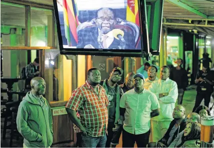  ?? AP Photo/Ben Curtis ?? > Zimbabwean­s watch the televised address by Robert Mugabe at a bar in downtown Harare last night