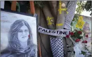  ?? (AP/Majdi Mohammed) ?? Yellow tape marks bullet holes on a tree alongside a memorial of a portrait and flowers on May 19 at the site where Palestinia­n American Al-Jazeera journalist Shireen Abu Akleh was shot and killed in the West Bank city of Jenin.