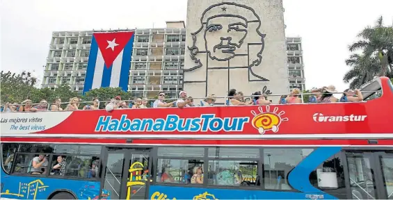  ?? EFE ?? Símbolos. Un micro con turistas recorre las calles de La Habana, con la imagen del Che Guevara y la bandera cubana de fondo, días atrás.