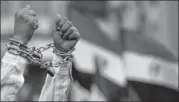  ??  ?? A protester shows his chained hands during a rally Friday against a constituti­on drafted by Islamist supporters of President Mohammed Morsi in Cairo. At least 19 people were injured in protests.