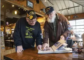  ?? READING EAGLE ?? Vietnam Veterans Rick Weitzel, left, and John Henschel look at photos Henschel has from their time serving together in the Air Force. At Mission Barbeque in Wyomissing where they met and spent time catching up.
