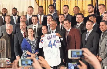  ?? GEOFF BURKE, USA TODAY SPORTS ?? President Obama holds up his new Cubs jersey and poses for photos at the White House ceremony honoring the 2016 World Series champions. At left is Cubs co-owner Laura Ricketts.