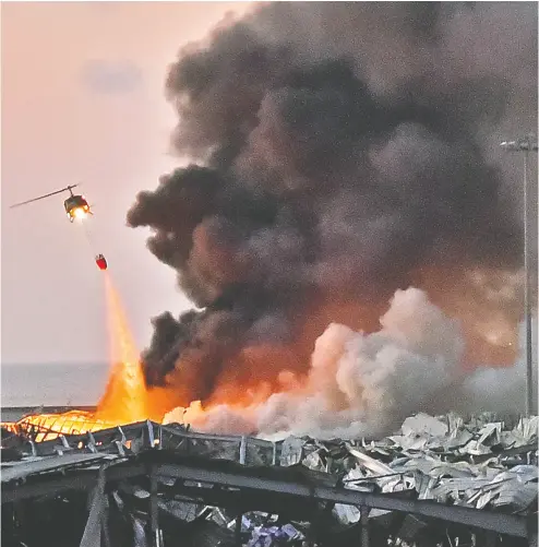  ?? STR / AFP VIA GETTY IMAGES ?? A helicopter assists in firefighti­ng efforts at the scene of Tuesday’s deadly blast in the Lebanese capital of Beirut.
Prime Minister Hassan Diab said that those responsibl­e for the explosion will be held accountabl­e.