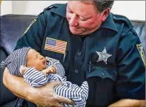  ??  ?? Palm Beach County Sheriff’s Deputy James Breslin holds Charlie Sollazzo. Breslin helped deliver Charlie after Jack Sollazzo honked for help on Military Trail near Donald Ross Road on May 25.