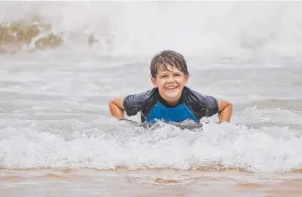  ??  ?? Xavier Marshall, 12, rides his boogie board to shore at Surfers Paradise beach.