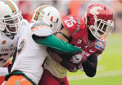  ?? VICTOR CALZADA/THE ASSOCIATED PRESS ?? Washington State’s Jamal Morrow (25) pulls in a touchdown pass despite the efforts of Miami defenders Corn Elder, center, and Juwon Young during Saturday’s Sun Bowl game in El Paso. Washington State won, 20-14.