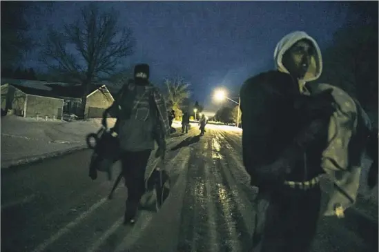  ?? Photograph­s by Robert Gauthier Los Angeles Times ?? ASYLUM SEEKERS make their way through Emerson at 6:30 a.m. after slipping into Canada. Many who have made the trek were unprepared for the harsh weather.