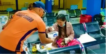  ?? PHOTOGRAPH COURTESY OF PCG ?? PHILIPPINE Coast Guard member hands food to a stranded passenger in Nasipit Port, Agusan del Norte.