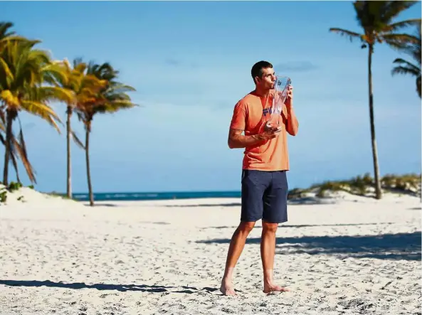  ??  ?? Sweet taste of victory: John Isner kissing the Butch Bucholz trophy on Crandon Park Beach after his three-set win against Alexander Zverev in the men’s singles final of the Miami Open on Sunday. — AFP