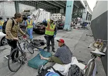  ?? AP ?? A San Francisco city worker tells a homeless man that the area next to him is about to be power washed and points to an area where he might want to move.