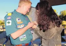  ?? TODD DICKSON/MOUNTAIN VIEW TELEGRAPH ?? Matthew Lindeman has his Medal of Merit pinned onto his Boy Scout uniform by his mother, Amy Lindeman, in recognitio­n of his efforts to protect the family ranch, animals and property during last year’s Dog Head Fire.