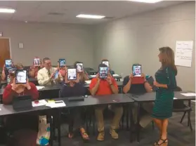  ??  ?? Teachers hold iPads to their faces as Robin Hunter teaches a class on using applicatio­ns on iPad to engage students. Hunter is a foundation­s coach in instructio­nal technology for Polk School District.