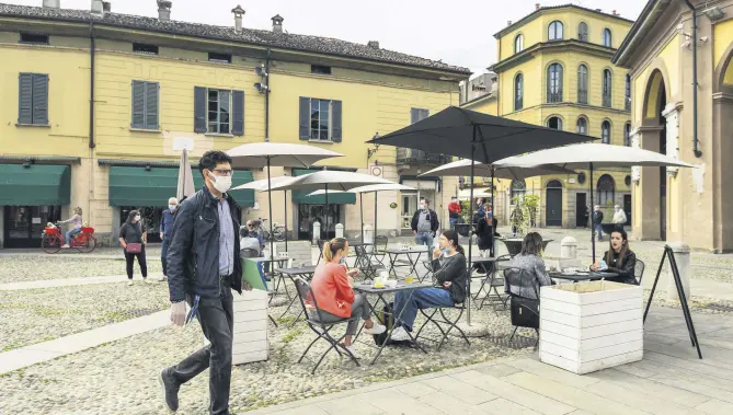  ??  ?? Residents have a drink at a cafe terrace and go about their activities at one of the villages in the epicenter of the coronaviru­s pandemic in central Codogno, southeast of Milan, Italy, May 20, 2020.