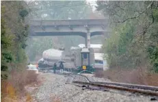  ?? — AFP ?? A derailed Amtrak car can be seen up the tracks near a crossing after an early morning collision with a CSX freight train on Sunday in Cayce, South Carolina.