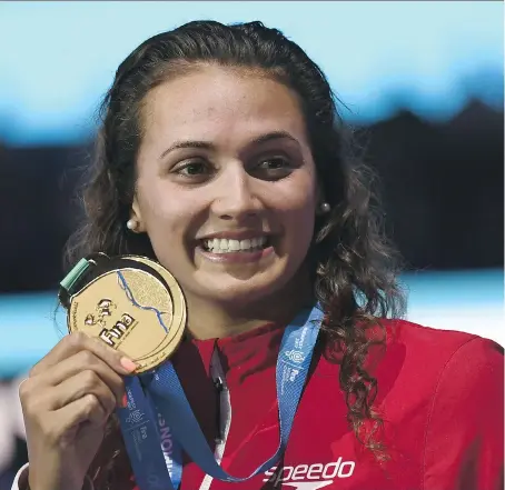 ?? CHRISTOPHE SIMON/AFP/GETTY IMAGES ?? Twenty-one-year-old Kylie Masse of LaSalle shows off her gold medal Tuesday after breaking the world record to win the women’s 100-metre backstroke at the 2017 FINA World Championsh­ips in Budapest, Hungary.