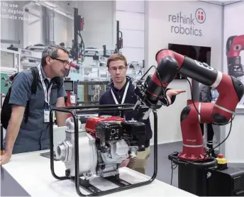  ??  ?? A staff member introduces an intelligen­t robot to a visitor at the Hanover Fair 2018 in Germany on April 23