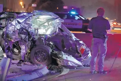  ?? JOE CAVARETTA/SOUTH FLORIDA SUN SENTINEL ?? A Broward Sheriff’s Office deputy examines the scene of an early morning hit-and-run on South Dixie Highway at 10th Street on Wednesday.