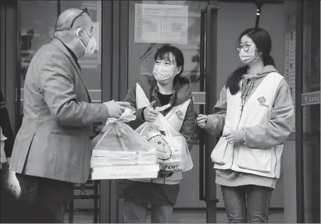  ?? JIANG KEHONG / XINHUA ?? Aladdin Colak (left) serves free meals to staff members at a community service center, in Fuzhou, Fujian province, in February.