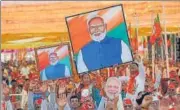  ?? AP ?? BJP supporters hold portraits of Prime Minister Narendra Modi during a public meeting, in Mehsana.