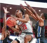  ?? Brett Coomer / Staff photograph­er ?? UH guard DeJon Jarreau (13) drives to the basket between Memphis’ Kareem Brewton Jr. , left, and Alex Lomax to score two of his 10 points in Sunday night’s 90-77 victory at Fertitta Center.